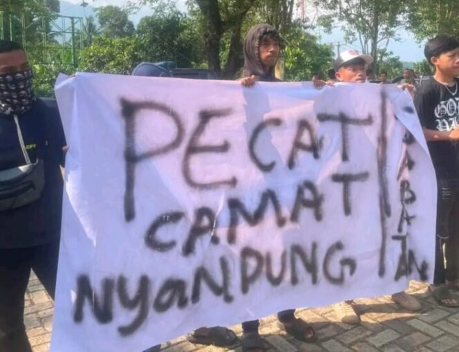 
					Sejumlah warga Kecamatan Saketi membentangkan spanduk bertuliskan desakan pencopotan Camat Saketi dalam aksi unjuk rasa di depan Kantor Kecamatan, Jumat (25/9/2025). (Foto: BantenPopuler.com)