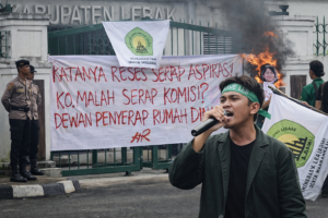Seorang mahasiswa IMALA menyampaikan orasi menggunakan pengeras suara di depan gerbang DPRD Kabupaten Lebak, Rabu (4/3/2026), dalam aksi menolak kenaikan dana reses 22,8 persen. (Foto: Dok. IMALA/Istimewa/Bantenpopuler.com)