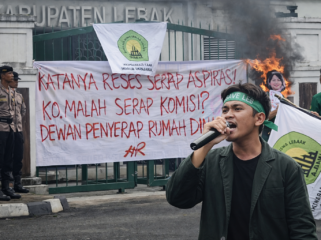 Seorang mahasiswa IMALA menyampaikan orasi menggunakan pengeras suara di depan gerbang DPRD Kabupaten Lebak, Rabu (4/3/2026), dalam aksi menolak kenaikan dana reses 22,8 persen. (Foto: Dok. IMALA/Istimewa/Bantenpopuler.com)