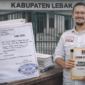 Ketua Umum BARALAK Nusantara, Yudistira, menunjukkan berkas laporan pengaduan dugaan korupsi APBD 2024–2025 di depan Gedung DPRD Kabupaten Lebak dengan bukti tanda terima dari Polda Banten.